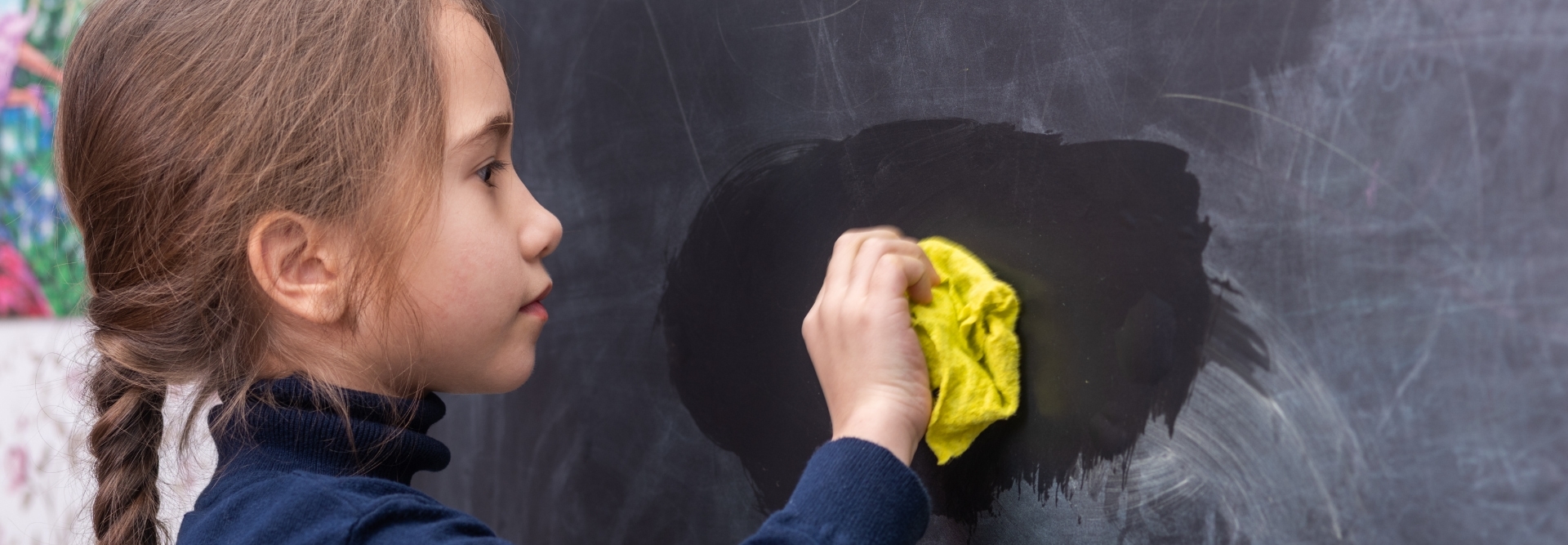 The girl wipes the blackboard.